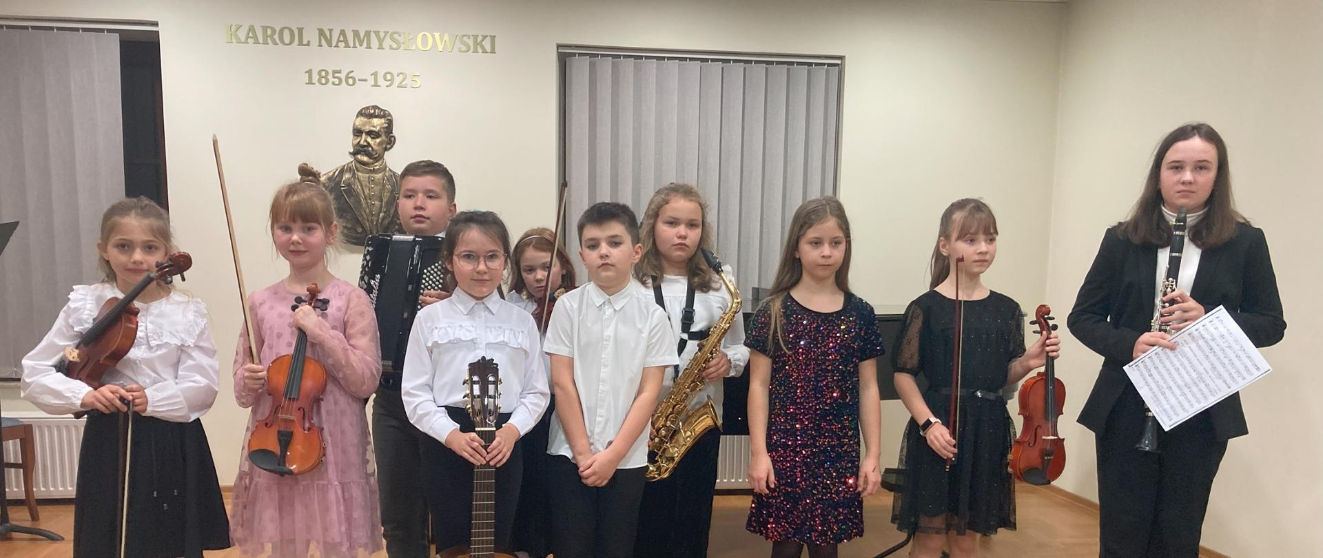 Popis klasy III cyklu 6-letniego. Sala koncertowa PSM I st. im. K. Namysłowskiego w Szczebrzeszynie. Na scenie po występach stoją uczniowie klasy III/6 - 10 osób. Ubrani na galowo, trzymaja w rękach swoje instrumenty.