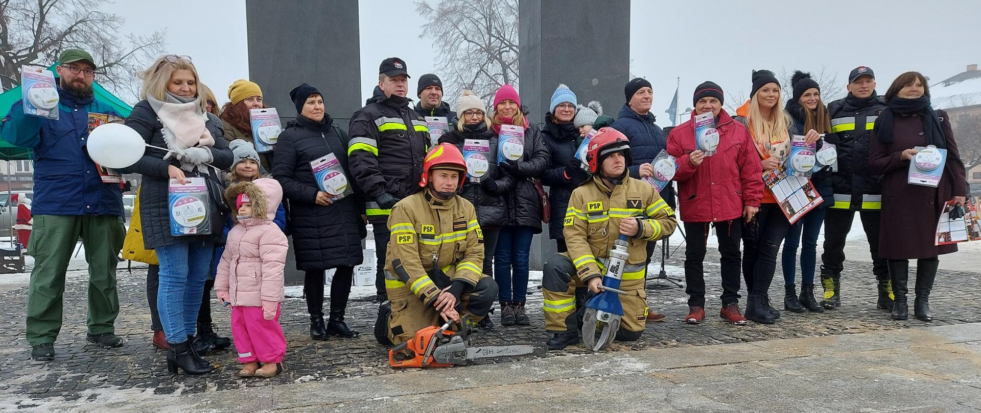Zdjęcie przedstawia strażaków Komendy Powiatowej PSP w Łasku z mieszkańcami podczas Kiermaszu Świątecznego