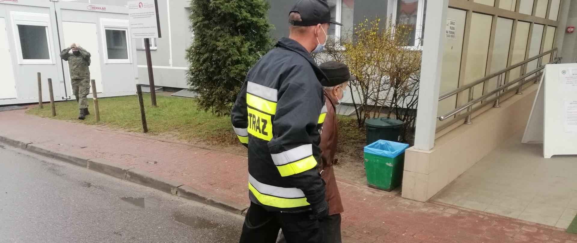 Druh OSP Krynki doprowadza starszego mężczyznę do punktu szczepień w Starachowicach ul. Radomska