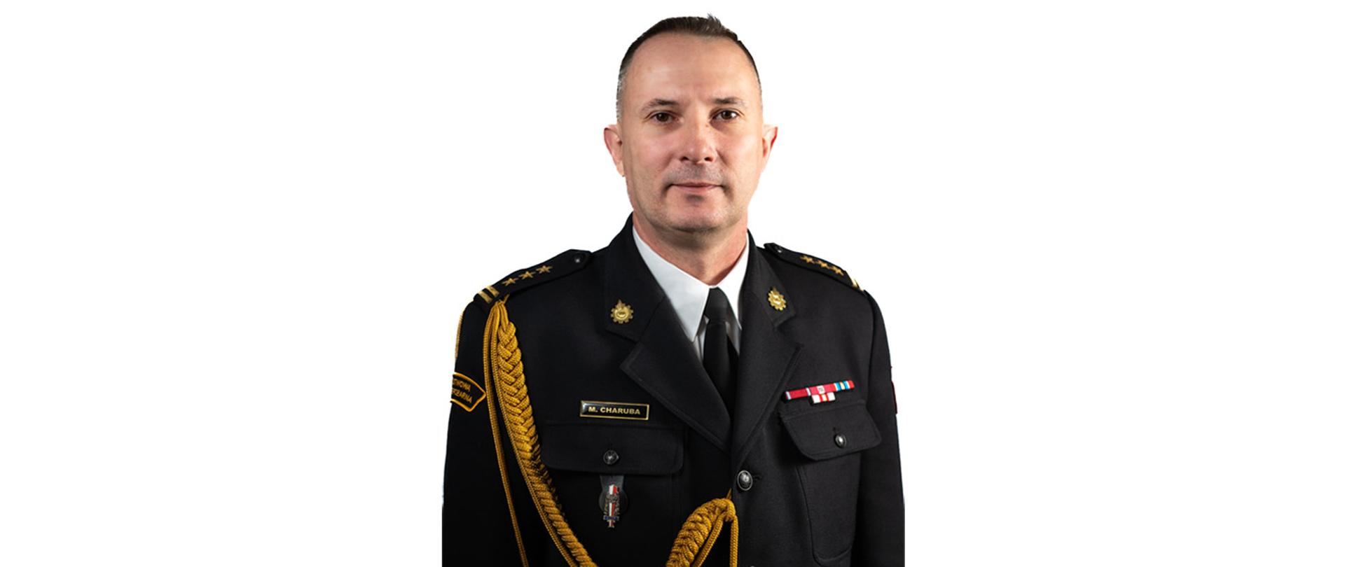 Na zdjęciu znajduje się mężczyzna w mundurze strażackim galowym ze sznurem. Zdjęcie na białym tle pozowane. 