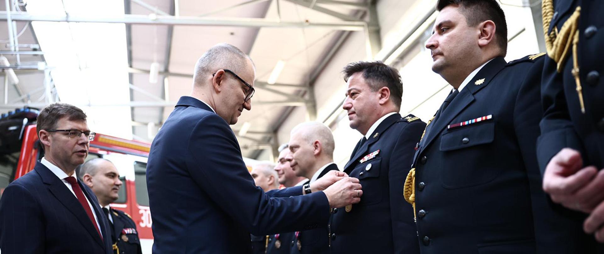 Na zdjęciu widać wiceministra Błażeja Pobożego wpinającego odznaczenie.