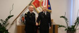 Na zdjęciu widać dwóch strażaków w umundurowaniu wyjściowym. W tle sztandar Komendy Głównej PSP.