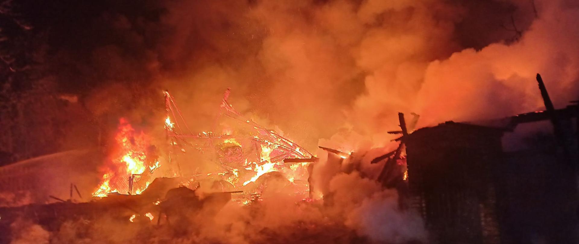 Widać budynek stodoły w całości objęty ogniem, jest noc
