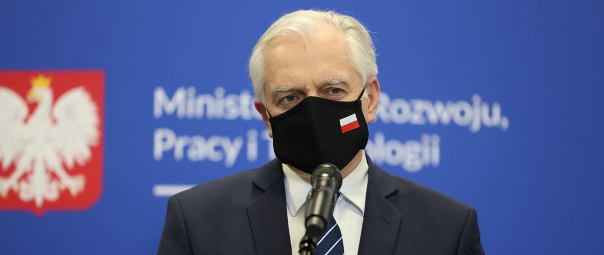 Wicepremier i minister rozwoju, pracy i technologii Jarosław Gowin na tle banera MRPiT z godłem Polski