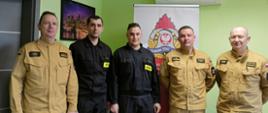 Zdjęcie przedstawia strażaków w pomieszczeniu podczas wspólnego zdjęcia po wręczeniu decyzji o zmianie stanowiska służbowego. 