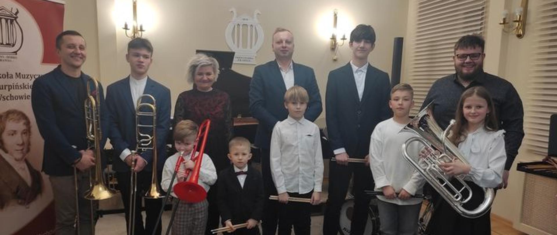 Wykonawcy koncertu półrocznego z nauczycielami w auli szkoły.