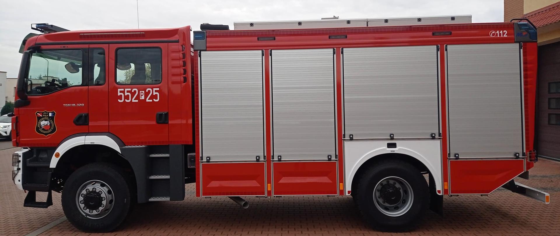 Zdjęcie przedstawia samochód pożarniczy, wykonane jest na zewnątrz, jest pochmurno. 