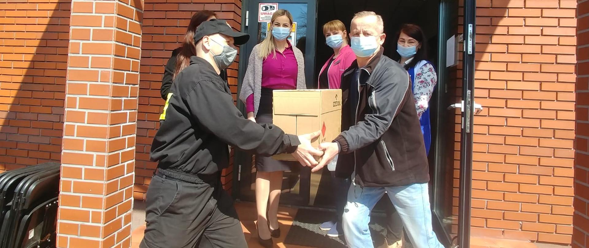Strażak dokonujący przekazania środków ochrony indywidualnej w punkcie szczepień zlokalizowanym w PCKR we Włoszczowie