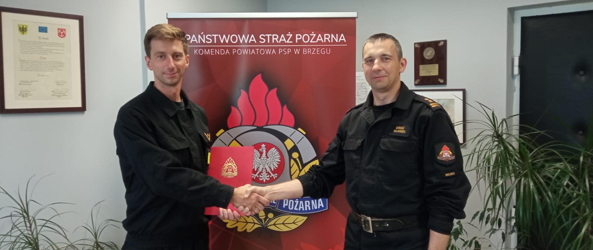 Awans na wyższe stanowisko służbowe - zdjęcie przedstawia Komendanta Powiatowego PSP w Brzegu podczas przekazania awansu na wyższe stanowisko służbowe mł. asp. Krzysztofowi Czarneckiemu