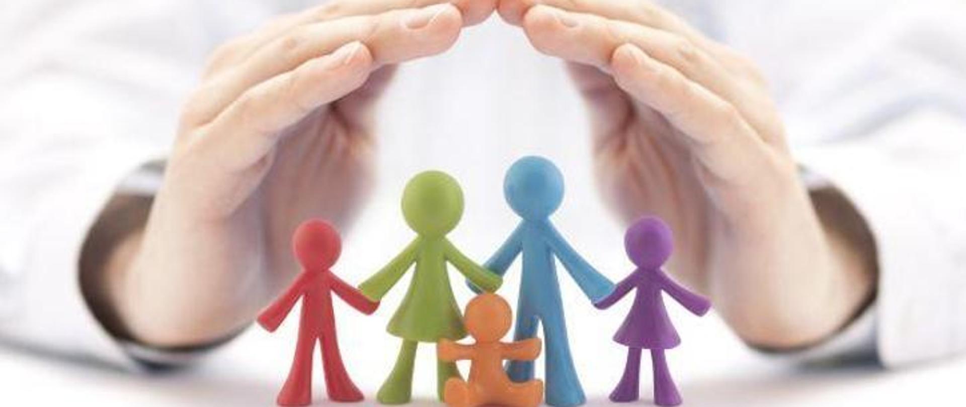 Dwie złożone ręce na małymi lalkami imitującymi małoletnich.