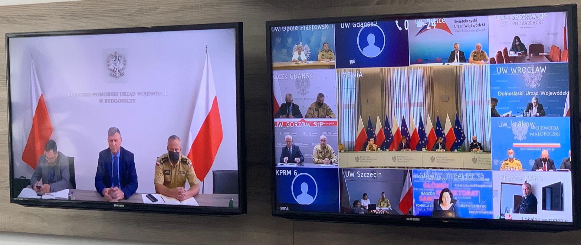 Na zdjęciu widać dwa telewizory, a na ich ekranach osoby biorące udział w wideokonferencji.