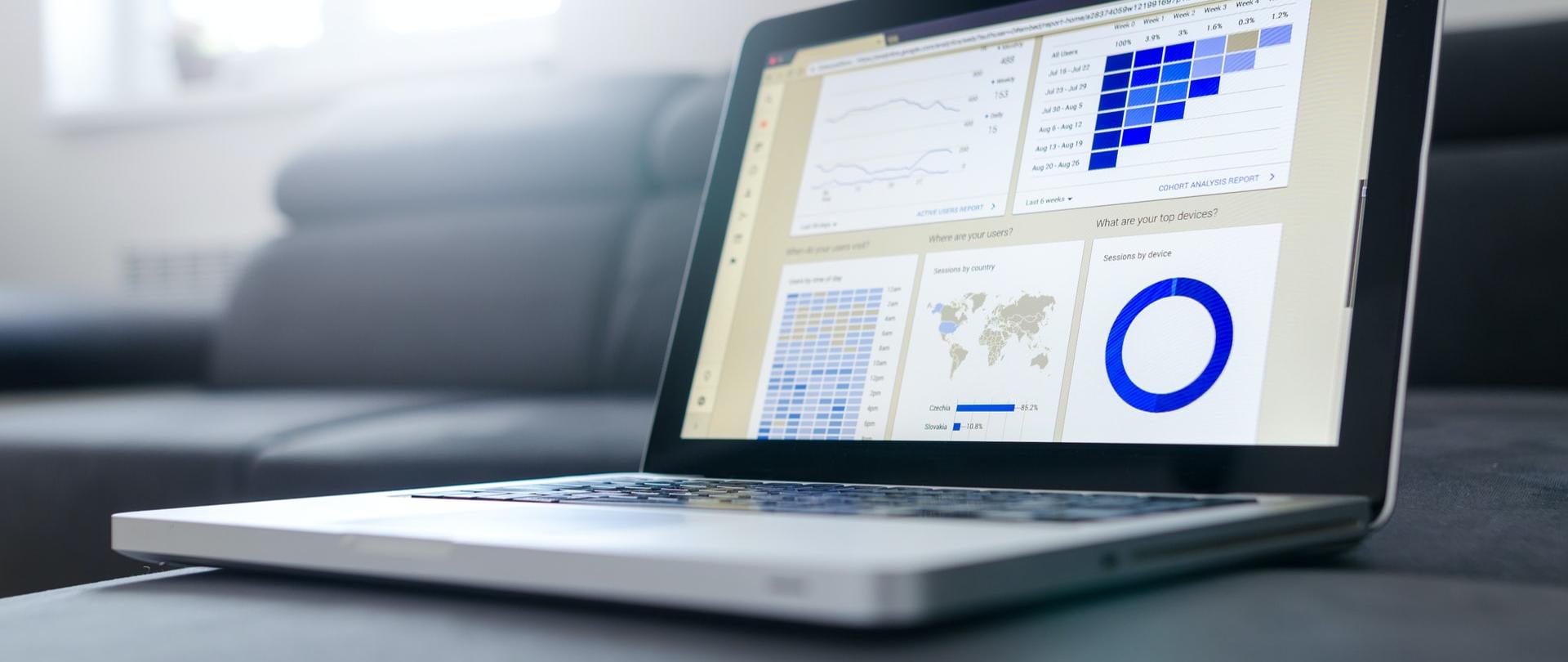 Laptop na stole z wyświetlonymi wykresami.