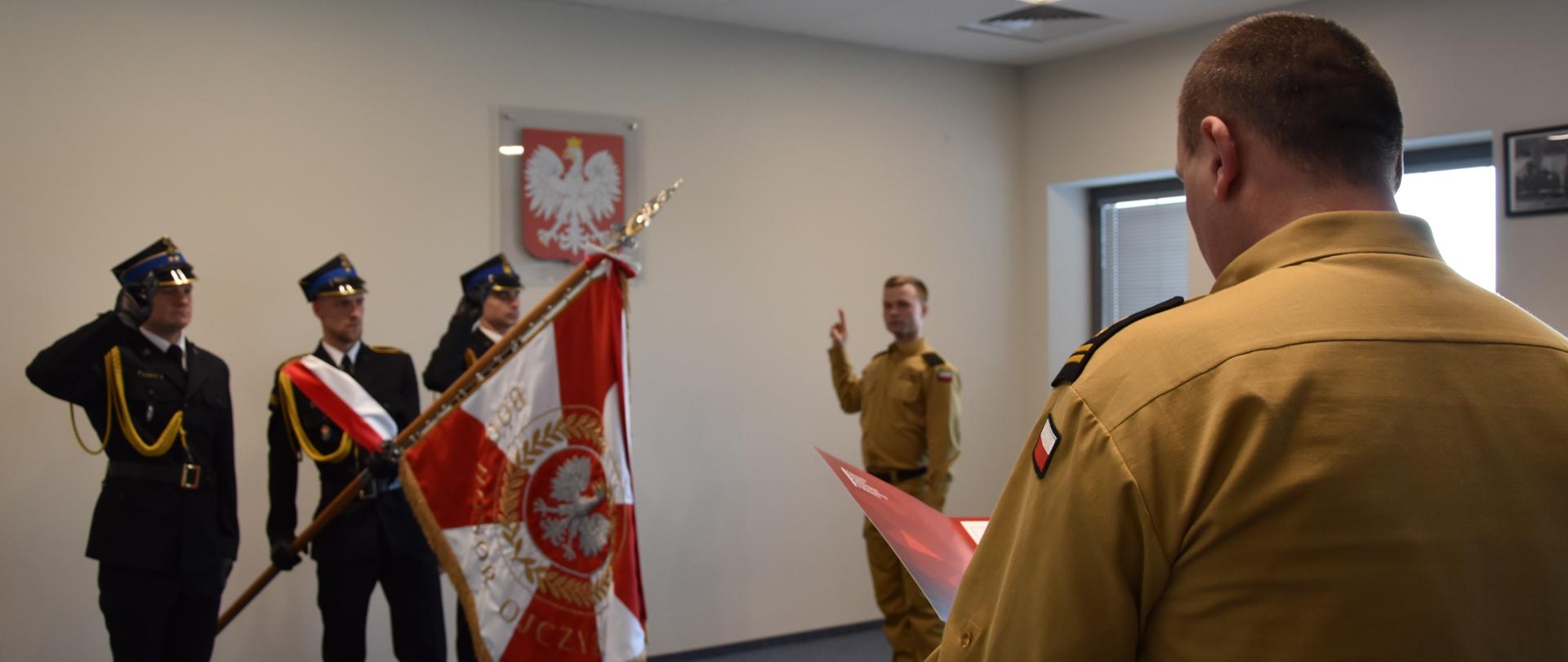 Uroczystość ślubowania, na pierwszym planie Komendant Miejski, dalej poczet sztandarowy i strażak składający ślubowanie. 