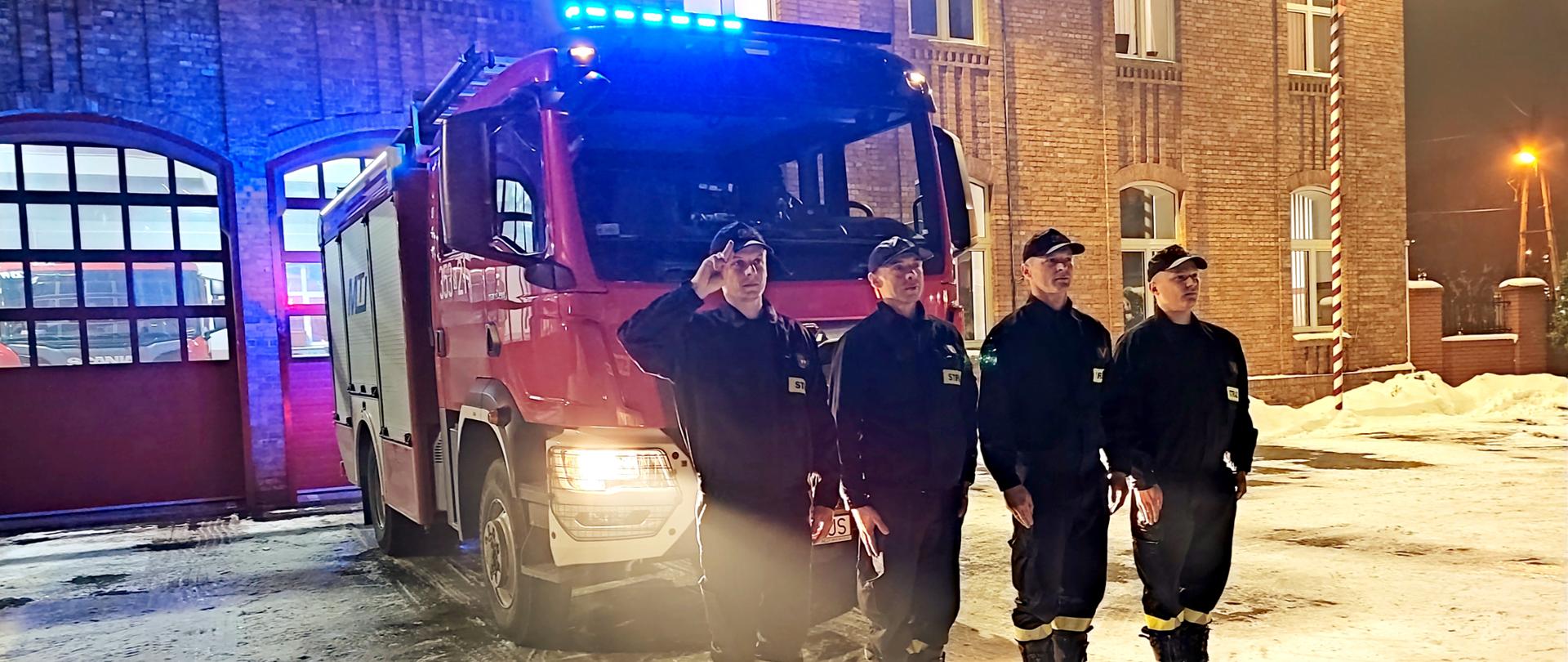 Na zdjęciu na tle samochodu pożarniczego z włączonymi sygnałami strażacy ustawieni w szeregu na baczność oddają hołd policjantom z Wrocławia.