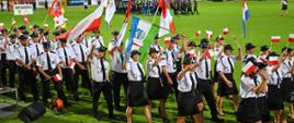 Drużyna żeńska i męska podczas uroczystości otwarcia zawodów, z flagami Polski na murawie stadionu