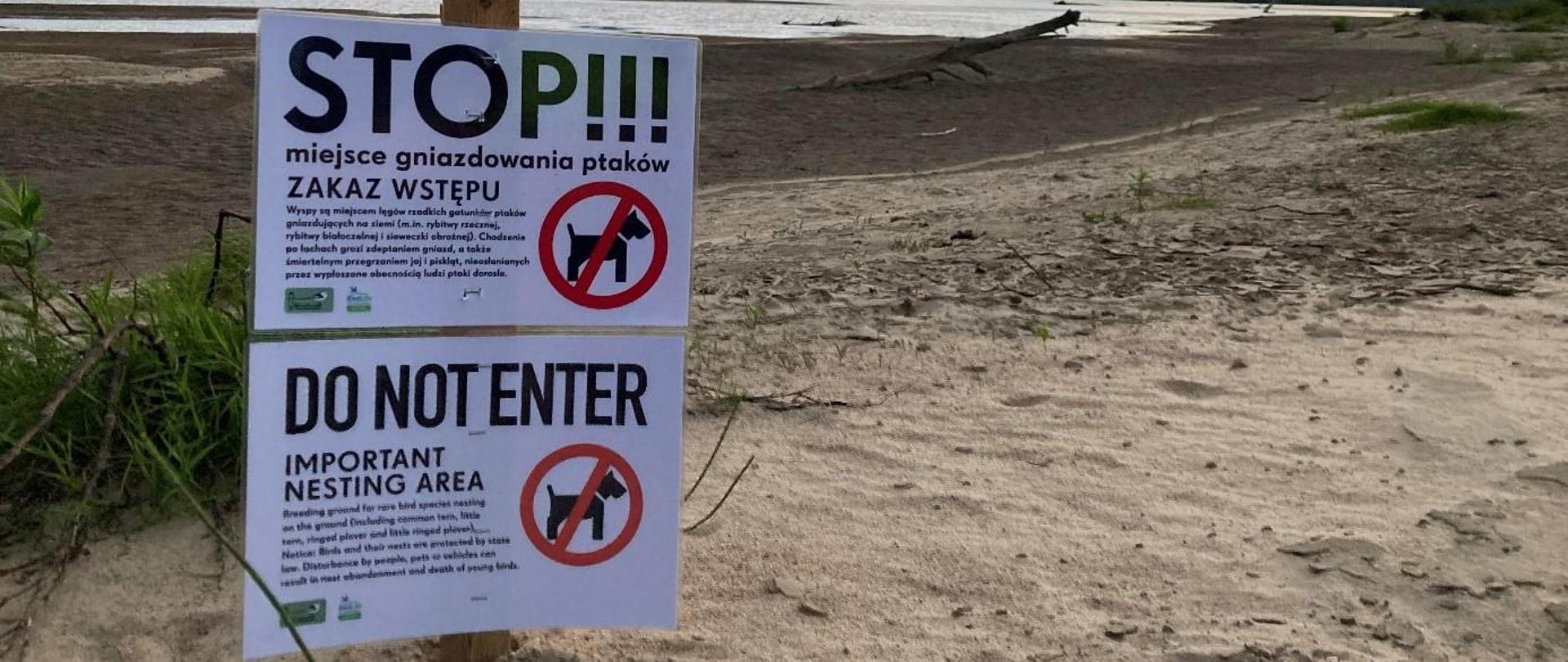 Dwie tabliczki na drewnianym słupku wbitym w piasek nad Wisłą, napis "Stop, miejsce gniazdowania ptaków, zakaz wstępu"