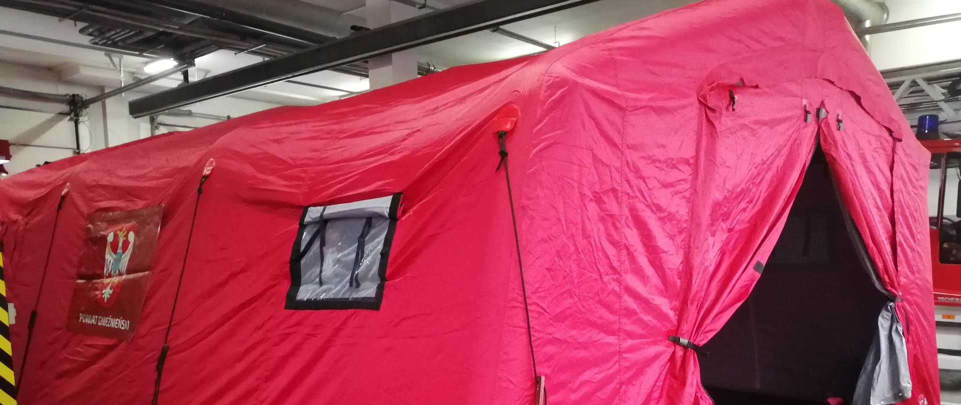 Czerwony namiot pneumatyczny stojący na szarej posadzce garażu