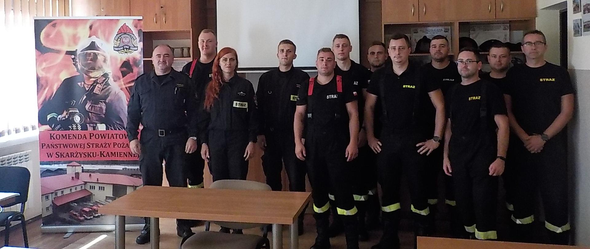 Na zdjęciu widać strażaków OSP biorących udział w szkoleniu naczelników OSP. Razem z nimi stoi wykładowca prowadzący zajęcia. Zdjęcie wykonano na świetlicy w budynku KP PSP Skarżysko-Kamienna. 
