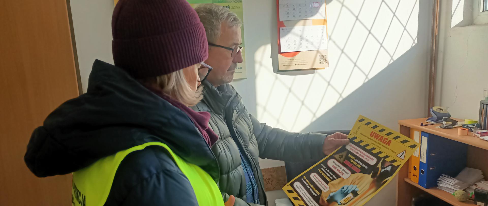 Mężczyzna i kobieta stoją obok siebie trzymając w rękach infografikę z napisem Uwaga