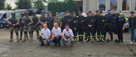 Służby mundurowe stoją w szeregu ustawieni do pamiątkowego zdjęcia, przed szeregiem kucają w białych koszulkach ratownicy medyczni