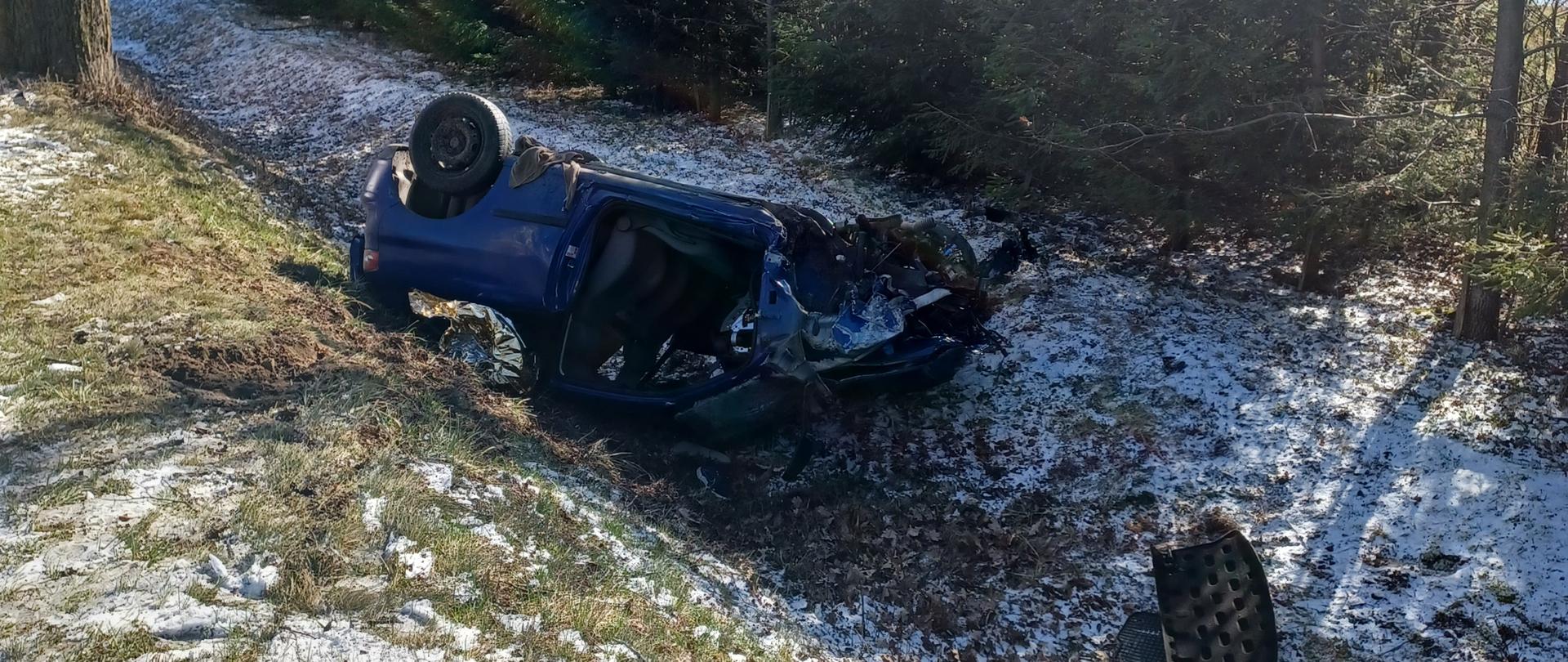 Rozbity samochód osobowy znajduje się w rowie na dachu. 