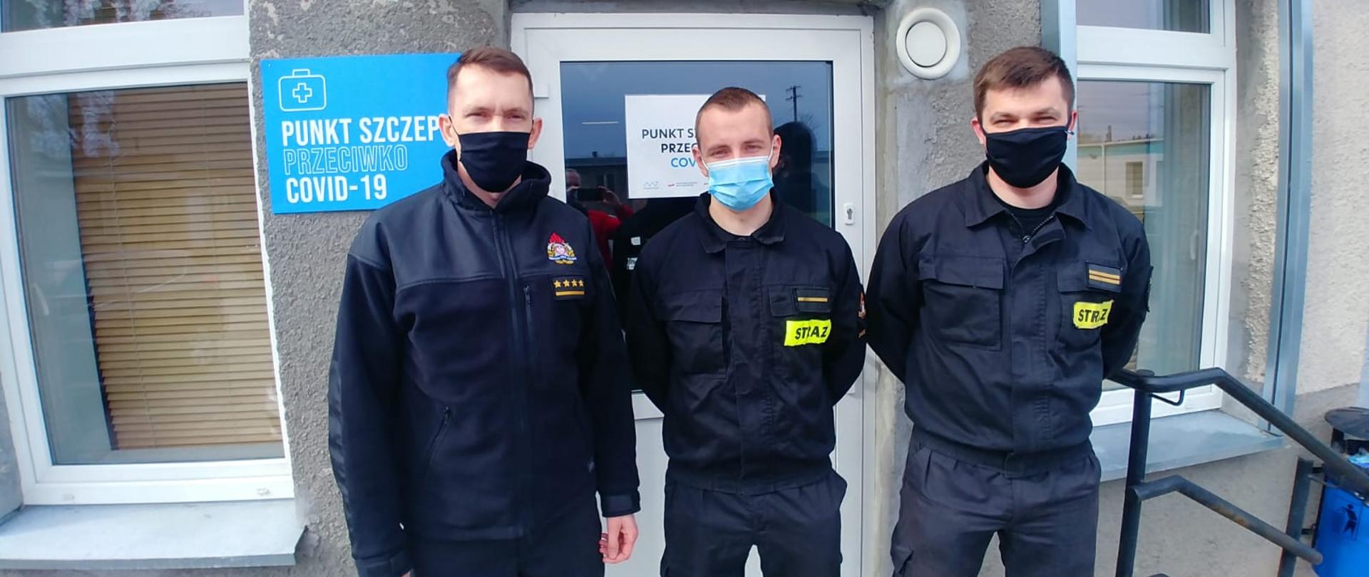 Przed punktem szczepień, przeciw COVID-19 stoi trzech funkcjonariuszy Komendy Powiatowej Państwowej Straży Pożarnej w Świeciu. 