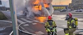 Pożar autobusu MZK. Strażacy podają pianę gaśniczą na palący się pojazd. Nad autobusem unosi się dym