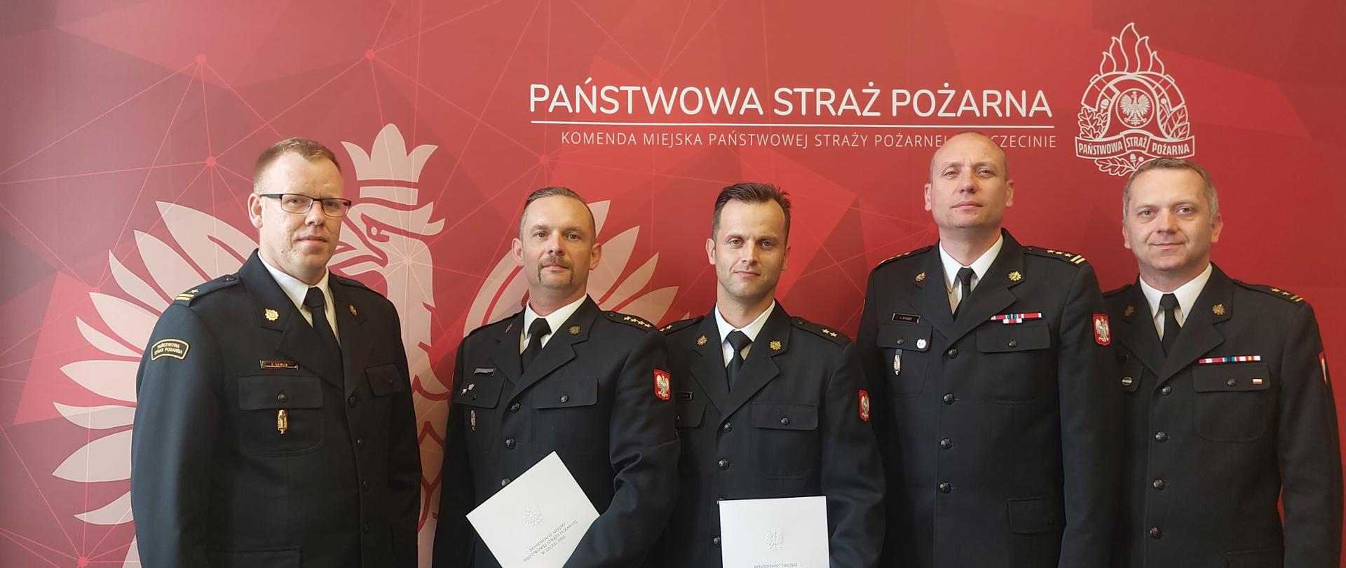 Od prawej na zdjęciu są bryg. Jacek Cyburt, st. bryg. Jacek Dziurdz, mł. kpt. Grzegorz Olszewski, st. kpt. Tomasz Obst, mł. bryg. Andrzej Gawlik. W tle czerwona grafika Państwowej Straży Pożarnej. 