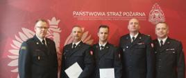 Od prawej na zdjęciu są bryg. Jacek Cyburt, st. bryg. Jacek Dziurdz, mł. kpt. Grzegorz Olszewski, st. kpt. Tomasz Obst, mł. bryg. Andrzej Gawlik. W tle czerwona grafika Państwowej Straży Pożarnej. 