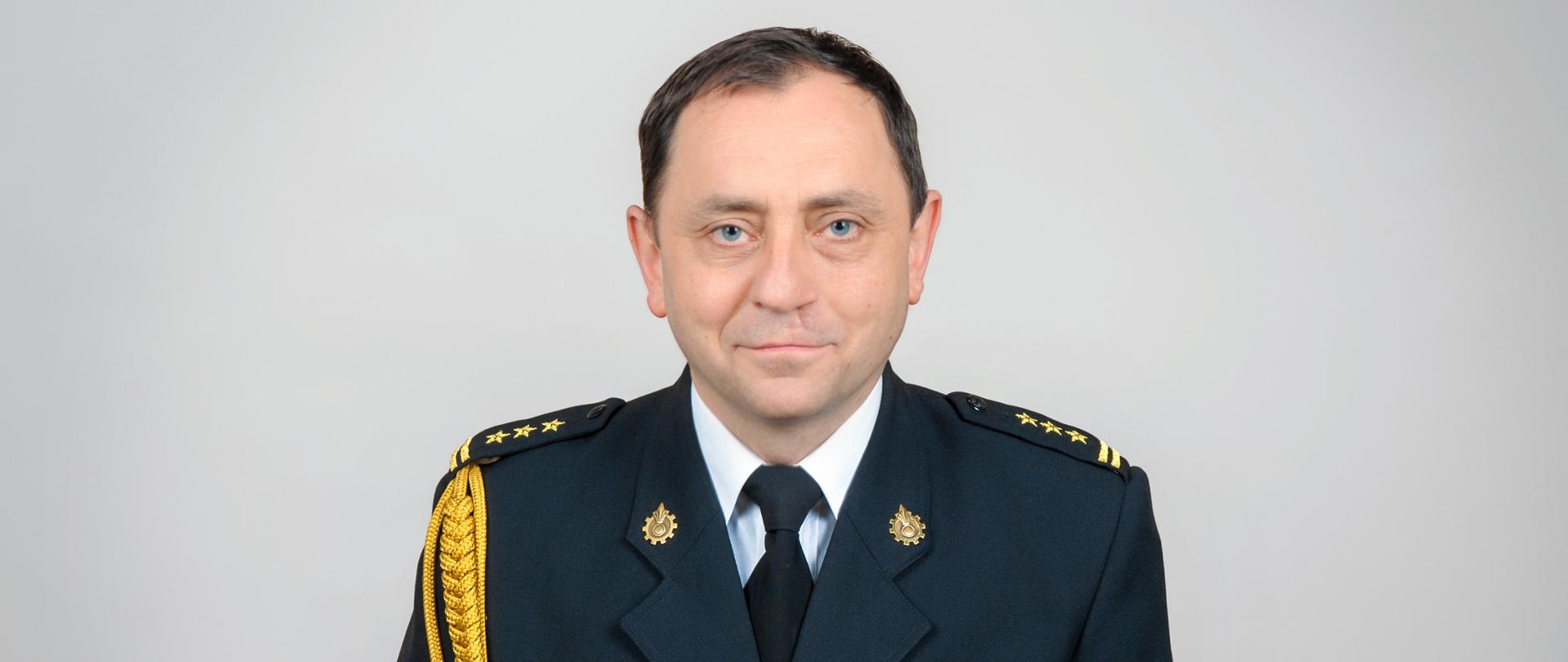 Zdjęcie portretowe st. bryg. Leszka Falbowskiego ubranego w mundur wyjściowy ze sznurem galowym i baretkami.
