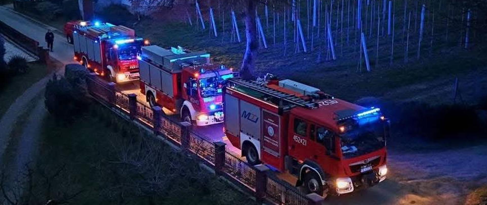 Na zdjęciu widoczne są samochody ratowniczo gaśnicze stojące na drodze w trakcie prowadzonych działań.