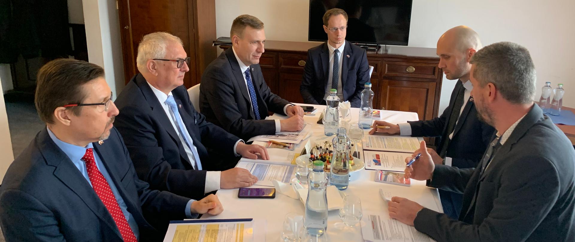 Wiceminister Grzegorz Piechowiak w trakcie spotkania w ramach Polsko-Słowackich Konsultacji Międzyrządowych, minister wraz z uczstnikami spotkania siedzą naprzeciwko siebie, z dokumentami przed sobą