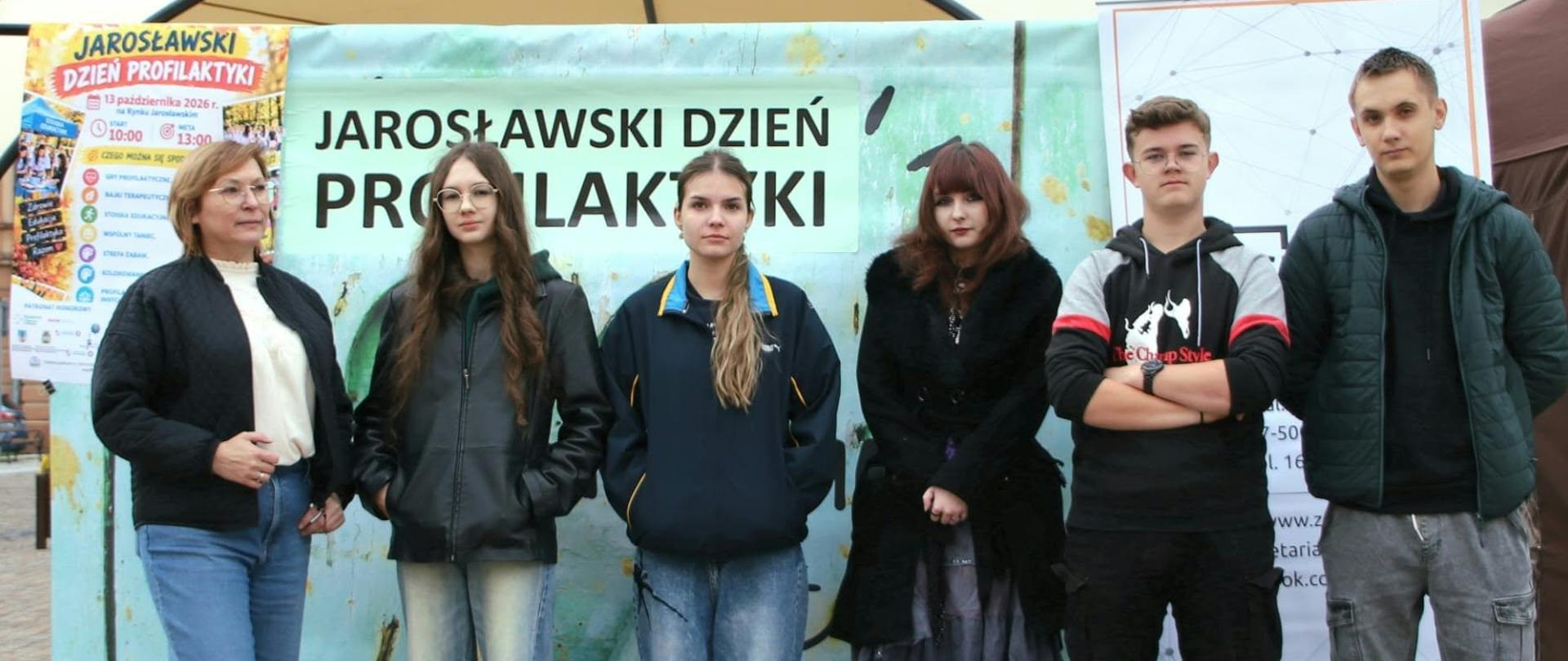 Na zdjęciu widzimy pięcioro uczniów – dwóch uczniów i trzy uczennice – wraz z opiekunem, którzy wspólnie pozują na tle ścianki promującej Jarosławski Dzień Profilaktyki.