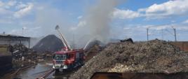 Pożar Przysieka Polska. na zdjęciu widać hałdy palących się odpadów, wozy strażackie i strażaków gaszących pożar.