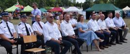 Zdjęcie przedstawia strażaków oraz inne osoby siedzące na krzesłach podczas wielkopolskiej biesiady 