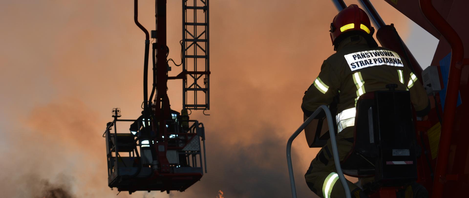 Strażacy w koszu podnośnika hydraulicznego podczas pożaru.