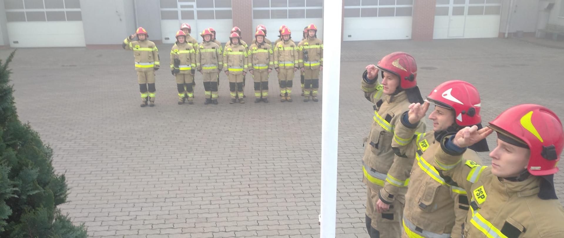 Strażacy w żółtych ubraniach specjalnych podczas uroczystej zbiórki z okazji Dnia Niepodległości na placu JRG3