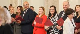 Minister Małgorzata Jarosińska-Jedynak podczas zaprzysiężenia nowego rządu Mateusza Morawieckiego, minister trzyma w dłoniach akt powołania na ministra funduszy i polityki regionalnej, po lewej stronie stoi minister rolnictwa i rozwoju wsi Anna Gębicka, zaś po prawej minister finansów Andrzej Kosztwoniak 
