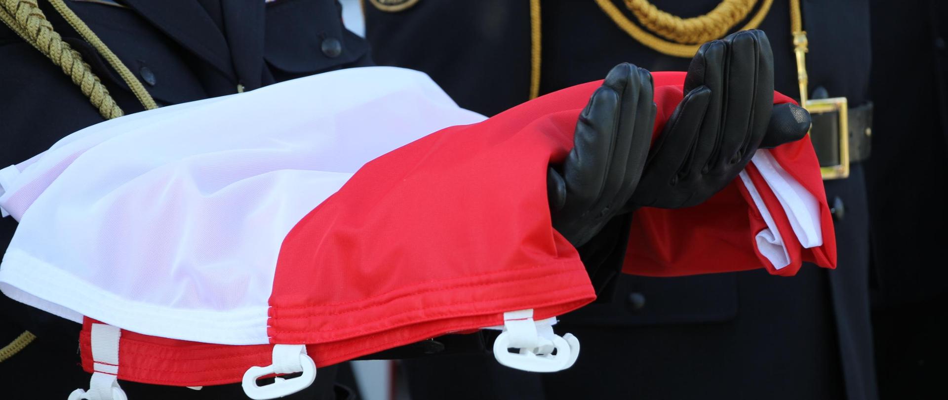 Flaga państwowa trzymana na rękach strażaka.