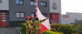 Na zdjęciu strażacy podnoszą flagę państwową oddając jej honory podczas uroczystej zbiórki