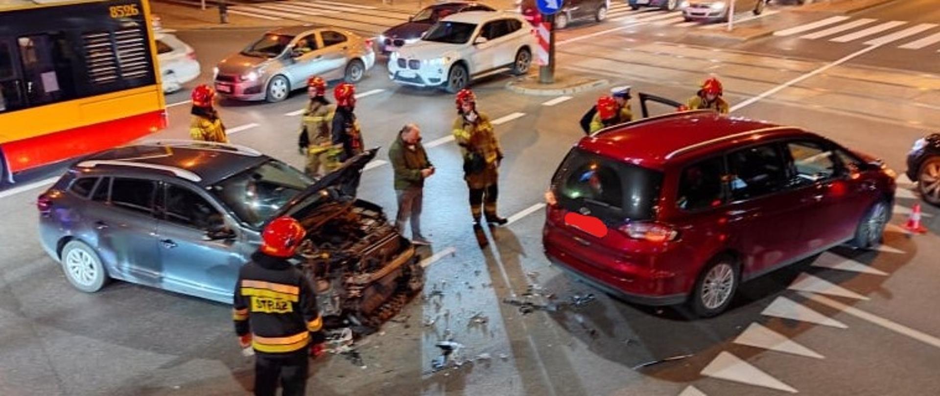 Na zdjęciu widoczne są dwa pojazdy które brały udział w wypadku, oraz pracujący strażacy
