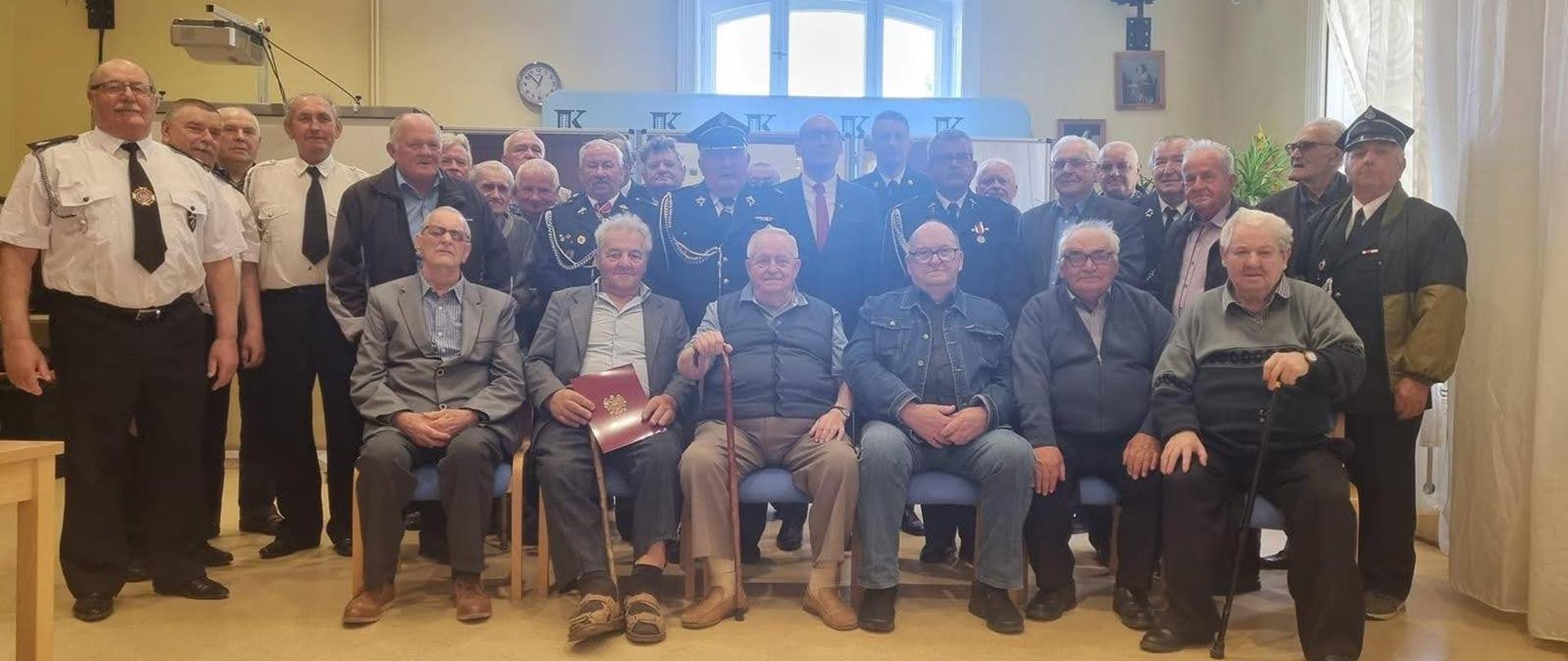 Na zdjęciu znajdują się druhowie z terenu Gminy Unisław wraz z Wójtem Gminy i Komendantem Powiatowym PSP w Chełmnie podczas wręczania decyzji o przyznaniu świadczenia ratowniczego. Zdjęcie wykonano w Gminnym Ośrodku Kultury w Unisławiu. 