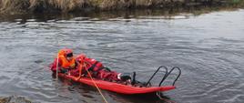 Dwóch strażaków na rzece wykonuje ćwiczenia z wykorzystaniem sań lodowych.