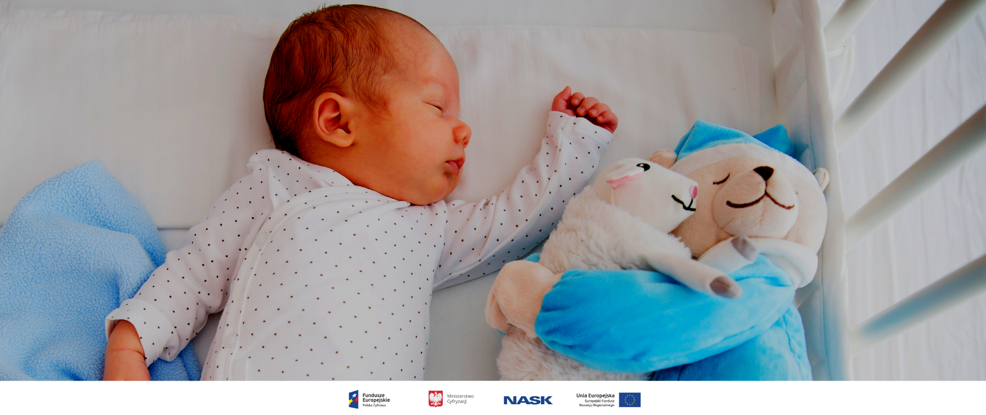 Zdjęcie niemowlaka w łóżeczku. Obok śpiącego dziecka leżą przytulanki.