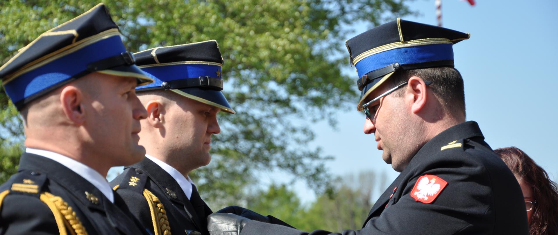 strażak przypina medal strażakowi