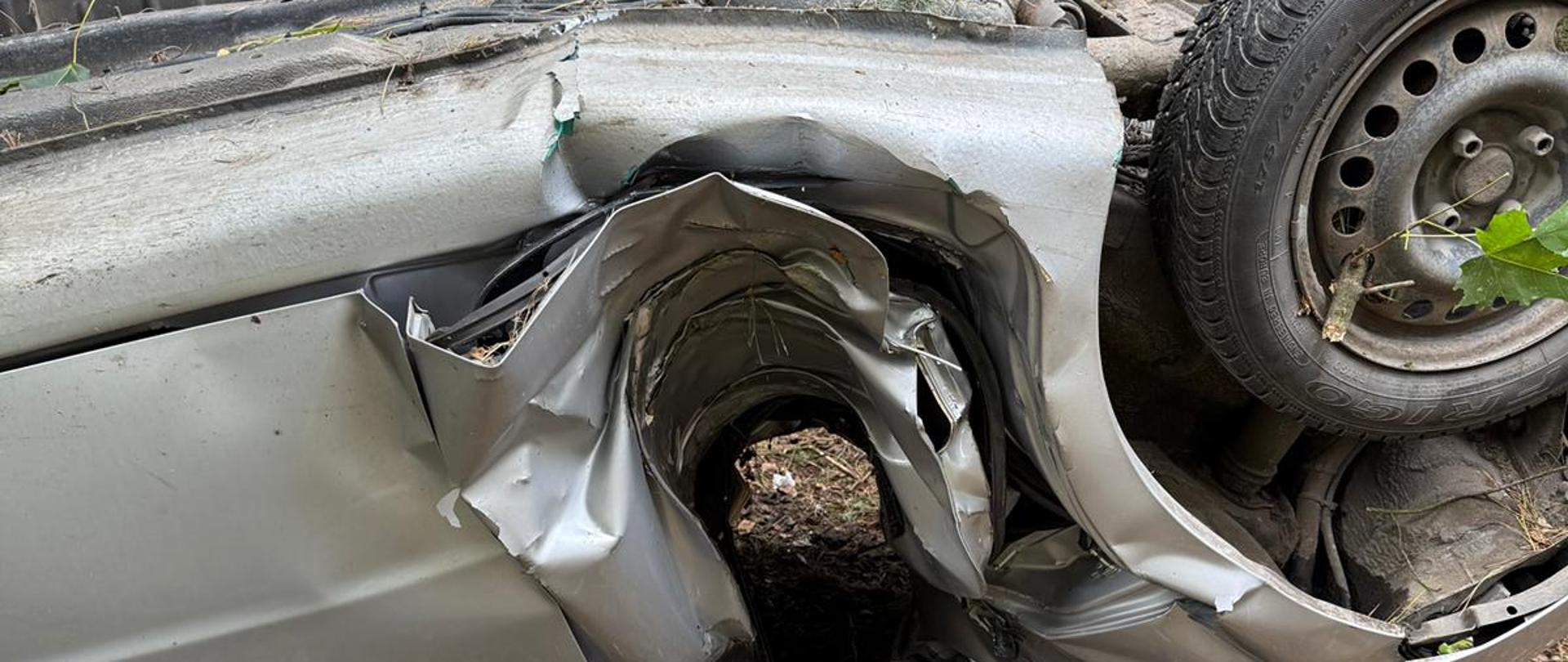 Na zdjeciu widać uszkodzenia pojazdu, samochód owinał sie dachem wokół drzewa na wysokości tylniego przedziału pasażerskiego.