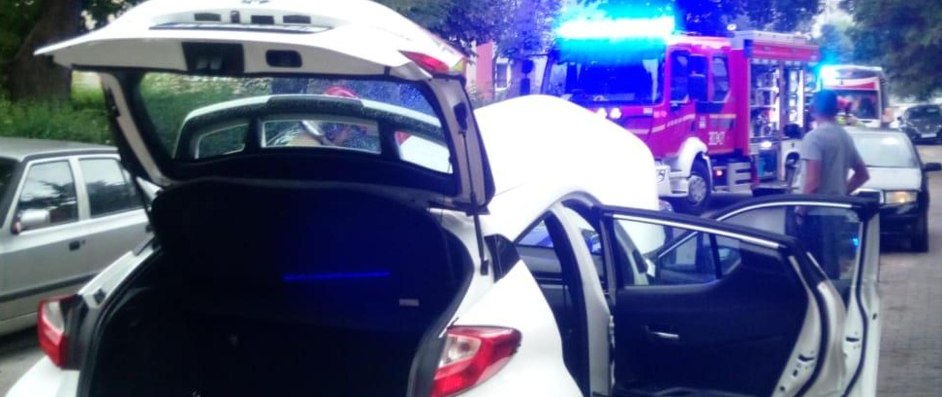 Zdjęcie przedstawia ulicę Urzędniczą oraz samochody, które zderzyły się na niej. W głębi samochód pożarniczy.