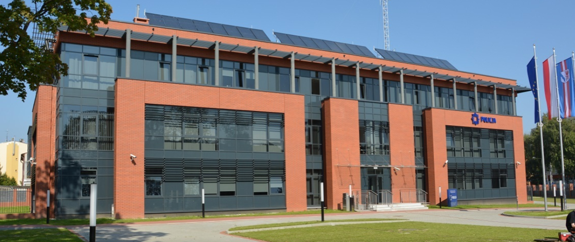 Frontowa elewacja Komendy Powiatowej Policji w Stargardzie, przeszklone przestrzenie w antracytowym kolorze z dodatkami ścian konstrukcyjnych w czerwonym klinkierze
