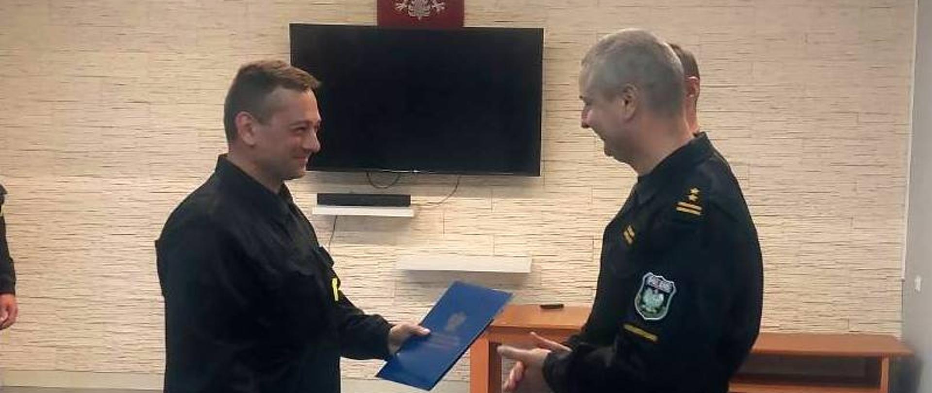 Na zdjęciu widać Komendanta Powiatowego PSP wręczającego decyzję o zakończeniu stażu st. str. Przemysławowi Dylewskiemu.