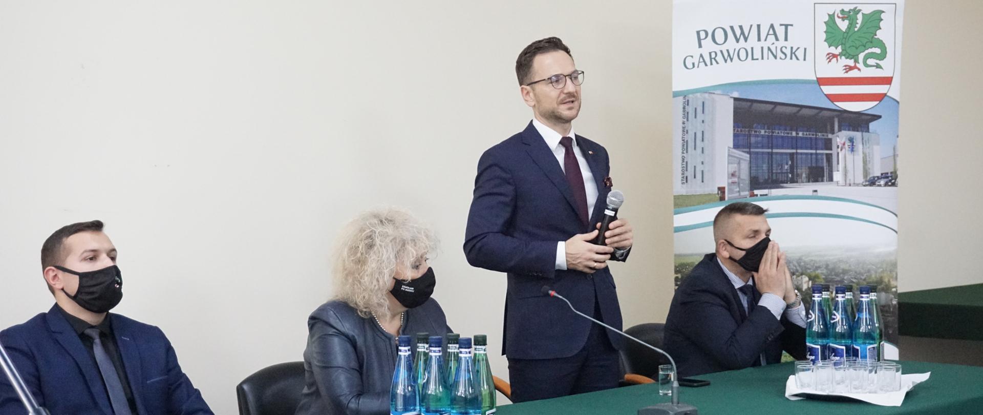 Cztery osoby za stołem konferencyjnym w tle rollup z napisem Powiat Garwoliński